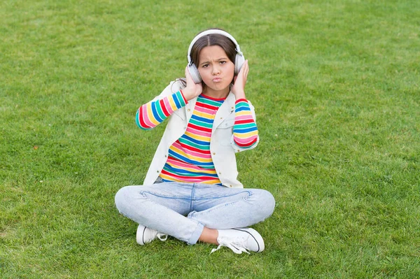 幸せな子供はヘッドフォンで音楽を聴く。緑の草の上の少女。子供は自然公園で歌を楽しむ。幸せな子供時代のコンセプト。デジタル機器を現代の生活に活用します。女子高生は屋外でリラックス — ストック写真