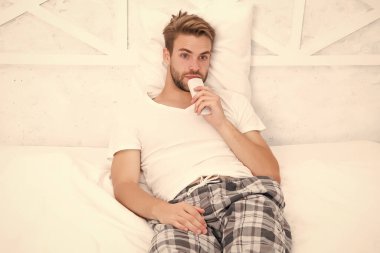 Uzaktan kumandalı pijamalı yakışıklı bir adam. Adam yatak odasında televizyon izliyor. Tembel pazar günü evde. Sabah programını izle. Adam televizyon izliyor. Yatakta uzaktan kumandayla kanal değiştir. Evde yatakta dinleniyor.