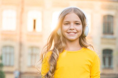 Kulaklarımı ve müziğimi açık tutuyorum. Mutlu bebek dışarıda kulaklık takıyor. Küçük çocuk stereo kulaklıkla müzik dinliyor. Modern tasarım kulaklıklar. Yeni teknoloji. Kulaklıklardan başka güvenilir bir şey yok.