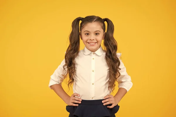 Welkom op school. Kleine school jongen met schattige glimlach. Kleine school kind glimlachend op gele achtergrond. Gelukkig klein meisje terug naar school. Schattig klein kind met lange brunette haar in formele slijtage — Stockfoto