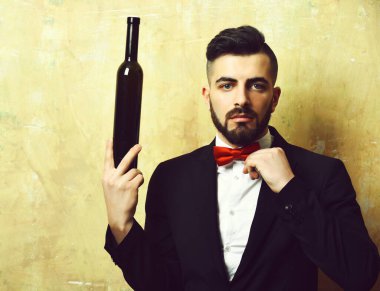 Sakallı beyaz yakalı işçi elinde bir şişe alkollü içki tutuyor.