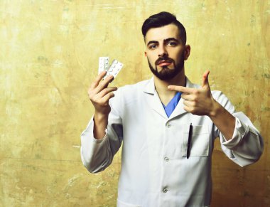 Sakallı ve kendine güveni olan doktor hapları gösteriyor.