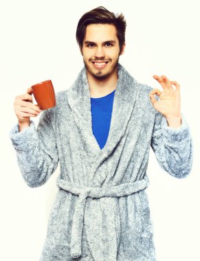 Terry bornozlu yakışıklı, sakallı, gülümseyen adam.