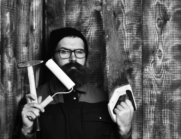 Γενειοφόρος ζωγράφος που κρατά διάφορα οικοδομικά εργαλεία με σοβαρό πρόσωπο — Φωτογραφία Αρχείου
