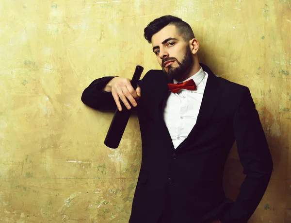 Homem com barba elegante em suite detém garrafa de vinho — Fotografia de Stock