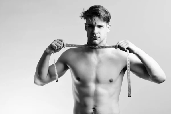 Hombre con cara seria y torso desnudo con cinta métrica — Foto de Stock