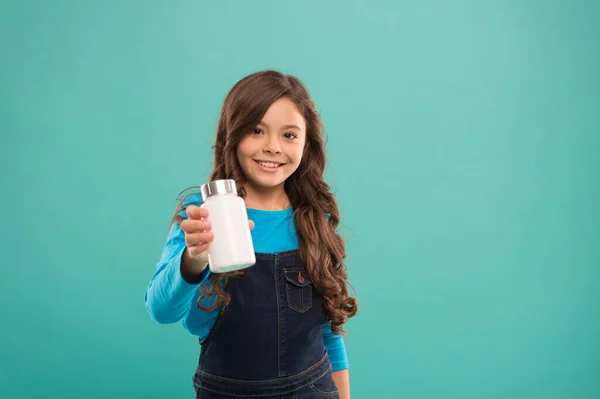 Σου προσφέρω αυτό. κοριτσάκι δείχνει κρέμα πλαστικό μπουκάλι. προϊόντα για παιδιά. παιδιά πολυβιταμίνες σε δοχείο. Διατηρήστε την ανοσία σας κατά την πανδημία του κορωνοϊού. Κορίτσι πρόκειται να πάρει χάπι ή βιταμίνη — Φωτογραφία Αρχείου