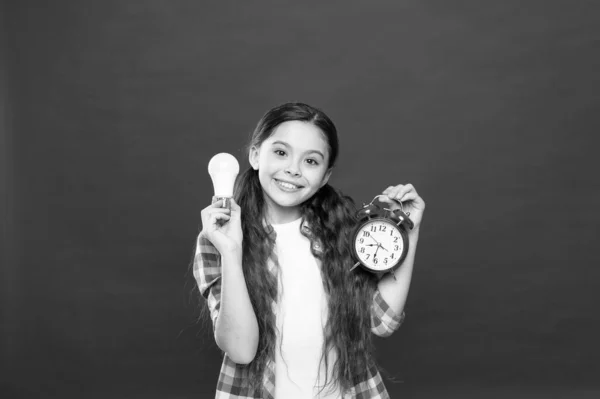 brainstorming and time management. Electricity energy. business idea. Time of lighting. Idea and inspiration. Time to find inspiration. small girl light bulb and clock. ring the alarm and light lamp