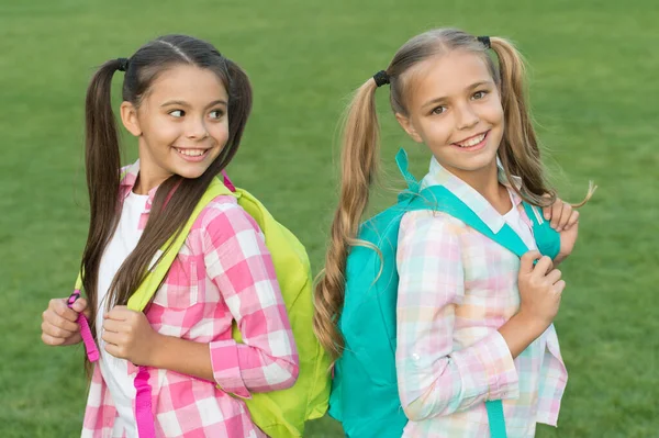 De vuelta a la escuela. Colegialas lindas con colas de caballo largas. Fin del año escolar. Alegre colegialas inteligentes. Colegialas felices al aire libre. Colegialas pequeñas con mochilas. Septiembre. Las vacaciones han terminado. —  Fotos de Stock