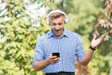 Ani sevinç. Görüntülü arama. Mutlu adam müziği akıllı telefondan seçiyor. Kablosuz kulaklık teknolojisi. Modern hayat. Mobil teknoloji. Uygulamayı güncelle. İletişim teknolojisi. Şaşırtıcı kullanıcı memnun