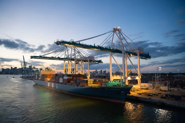 Miami, États-Unis - 01 mars 2016 : bateau de fret MOL Expeditor in cargo port. Navire porte-conteneurs et grues allumées en soirée. Transport maritime et côtier de marchandises par eau. Expédition et transport — Photo