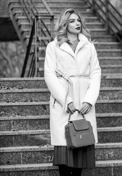 So nice. european winter. girl warm coat stairs background. faux fur coat fashion. stylish business lady leather bag. glamour girl look luxuriously. sexy blong woman red lipstick. autumn season