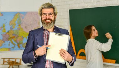 Okula dönelim. Koşucu öğrenci gelişimi. Öğretim malzemeleri. Kendisi bugün yok. Kara tahtada küçük bir kız. Öğrenci ve öğretmen sınıfta. Öğretmen doğru cevabı kontrol ediyor. Tutkuyla öğretmek