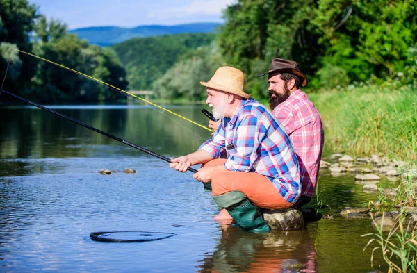 De wilde natuur. gepensioneerde vader en volwassen zoon met baard. Gelukkige vissers vriendschap. Twee mannelijke vrienden die samen vissen. vliegvissen hobby van mannen in geruit shirt. pensioenvisserij. Vangst en visserij — Stockfoto