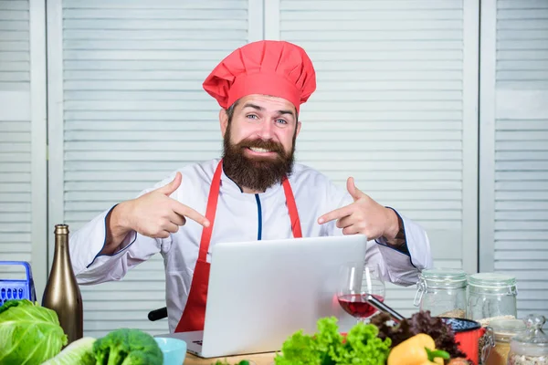 Man chef searching internet recipe cooking food. Elearning concept. Chef laptop read culinary recipes. Culinary school. Hipster in hat and apron learning how to cook online. Culinary education online