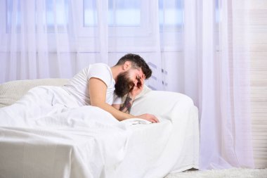 Yatakta uykulu bekar uyanmaya ya da uyumaya hazır. Sıkı çalış ya da kavramı yak. Tarafsız ses tonları. Yatakta yatan gömlekli adam, arka planda beyaz perde..