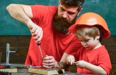 Baba, sakallı ebeveyn oğluna tornavida kullanmayı öğretiyor. Çocuk, babasıyla birlikte tornavida kullanmayı öğrenmekle meşgul. Tamirci ve atölye konsepti.