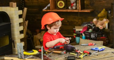 Atölyedeki küçük yardımcı. Yan gören çocuk vidayla oynuyor. Çocuk farklı araçlarla çalışmayı öğrenmekle meşgul.