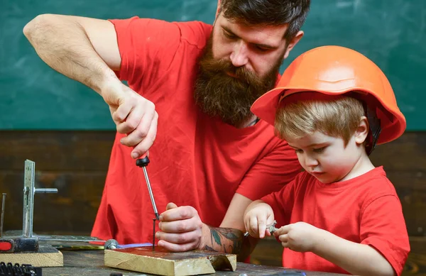 Отец, родитель с бородой учит маленького сына использовать отвёртку. Мальчик, ребенок, занятый в защитном шлеме, учится пользоваться отвёрткой с папой. Концепция мастерской и мастерской . — стоковое фото