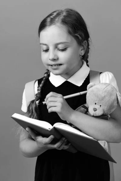 Ecole fille avec sourire et concentré visage isolé sur bleu — Photo