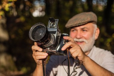 Kuşları izlemeyi seviyor. Yaşlı adam doğayı vurdu. Profesyonel fotoğrafçı. Mükemmel bir çerçeve. Eski fotoğrafçı çekim yapıyor. Elle ayarlar. Emeklilik hobisi. Deneyimli fotoğrafçı. Klasik kamera.