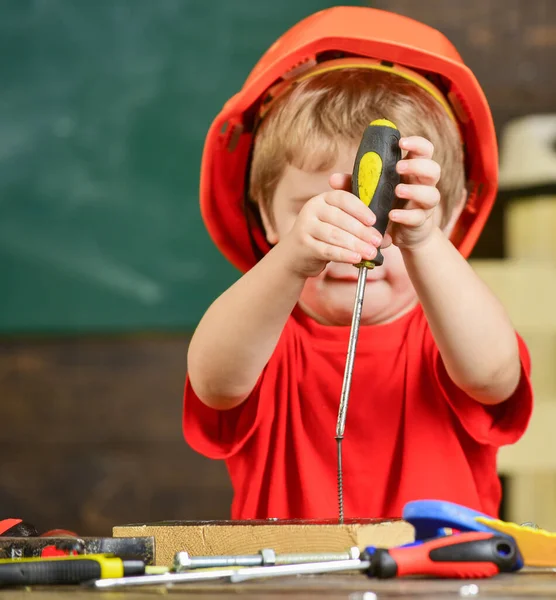 Small kid holding yellow tool in front of his face. Lovely boy playing with screwdrivers. Little repairman busy working