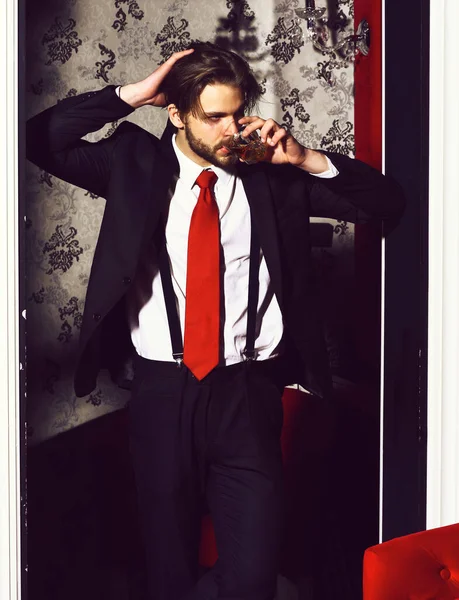 Homem barbudo, homem de negócios de terno, gravata vermelha segura copo de uísque — Fotografia de Stock