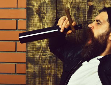 Sakallı, Kafkas hippisi elinde şişe, puro içiyor.