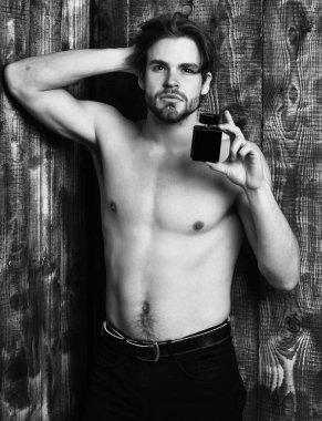 Beyaz sakallı seksi maço adam parfüm tutuyor.