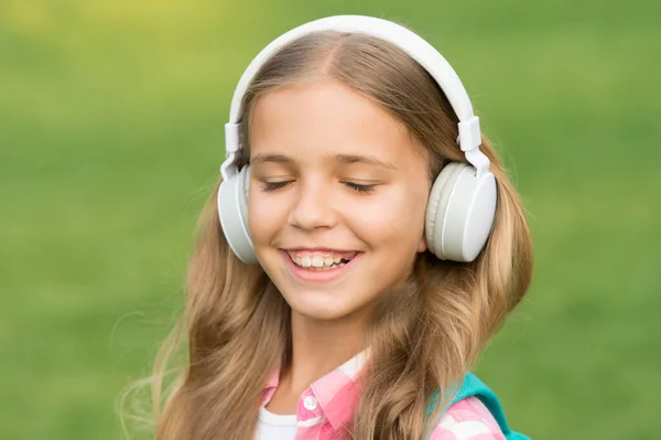 歩いている間に音楽を聞く。女の子のヘッドフォン音楽を聞いて。教育用ポッドキャスト。子供の女の子は音楽を楽しむ。楽しい時間だ。子供のヘッドフォンは音楽を聞く。オーディオブックのコンセプト。オーディオレッスンの勉強 — ストック写真