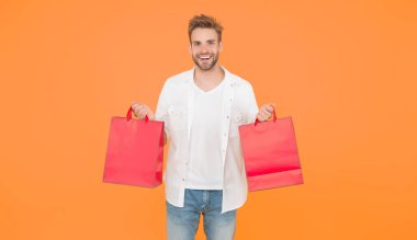 Adam satın aldığına sevindi. İnternetten alışveriş başarılı. Erkek alışverişçi paketleri tutar. Mallarla dolu bir alışveriş çantası. Satış sırasında para biriktirmek. Siber pazartesi konsepti. erkekler için eşyalar