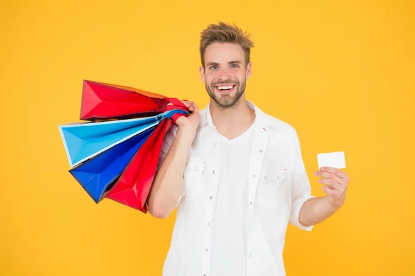 Hombre feliz compra uso método de pago. shopaholic vació su tarjeta de crédito. comprar regalos y regalos en línea. asistente de tienda con bolsas de embalaje y tarjeta de descuento. servicio de entrega de compra — Foto de Stock