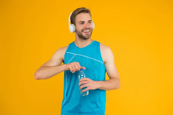 Celebrating health. Healthy man open water bottle. Fitness coach wear headphones. Water and hydration. Health benefits. Increasing water level and health. Fitness for health resolution — Stock Photo, Image