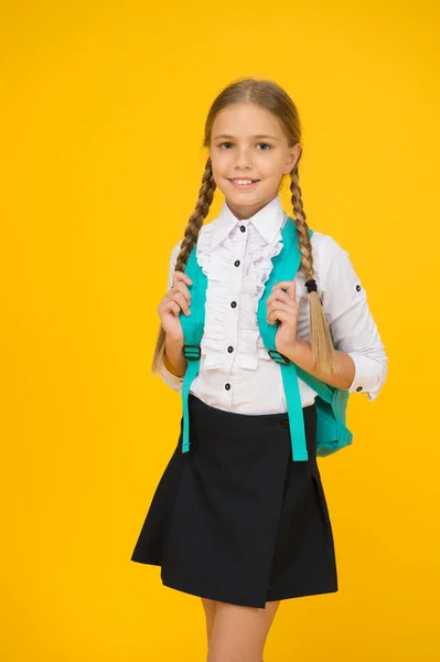 Meisje in uniform draagt rugzak. pure schoonheid. kind na de les. School mode stijl. slim uitziende student op gele achtergrond. modern onderwijsconcept. terug naar school — Stockfoto