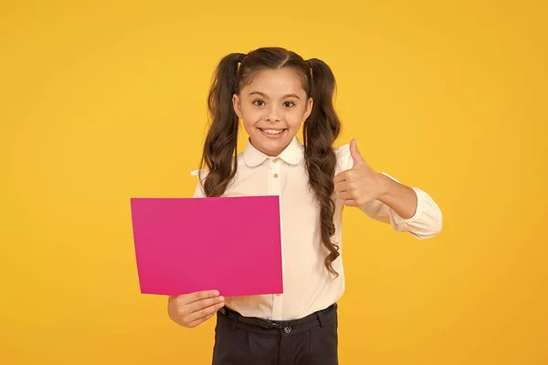 Votre publicité se lève les pouces. Joyeux petit enfant montrant les pouces vers le haut pour la publicité de retour à l'école sur fond jaune. Petite fille publicité produit ou événement. Éducation publicitaire, espace de copie — Photo