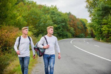 Sırt çantalı bir adam yolda otostop çekiyor. Yaz tatili. Turist gezgini otomobil durağında durur. Bütçe yolcuları. Sırt çantaları yolda beraber yürüyorlar. Yol boyunca yürüyen ikizler. Macera ve keşif