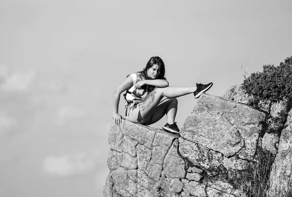 På gränsen till världen. Kvinna sitter på kanten av klippan i höga berg blå himmel bakgrund. Vandring i lugn och ro. Njut av utsikten. Extremt koncept. Turistvandrare flicka avkopplande kant klippa. Farlig avslappning — Stockfoto