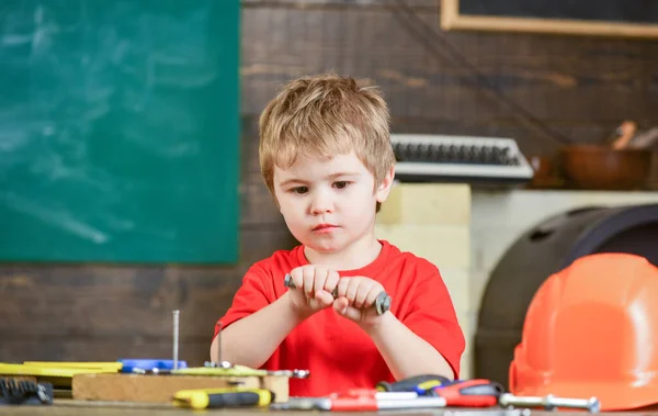 Niño jugando con perno metálico largo. Un chico concentrado explorando cosas nuevas. Niño aislado en taller — Foto de Stock