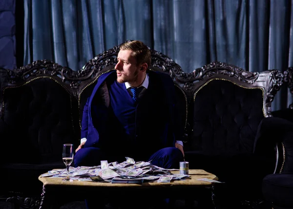 Man in suit, businessman sit in dark luxury interior background.