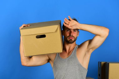 Mavi arka planda ağır kartonlu ve yorgun görünen adam.