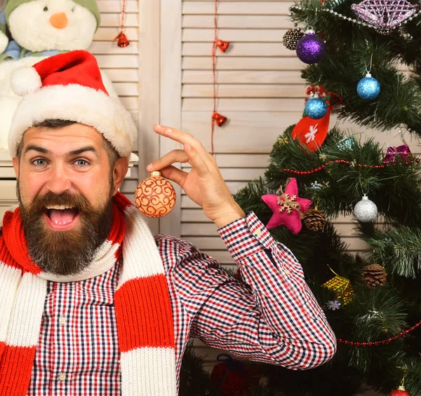 Mann mit Bart hält goldene Weihnachtskugeln als Ohrringe — Stockfoto
