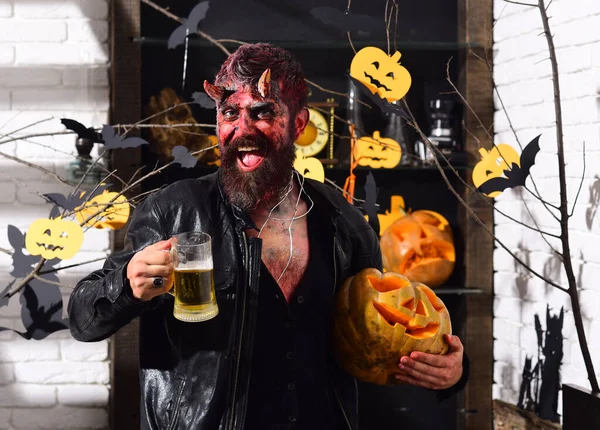 Man wearing scary makeup holds mug of beer