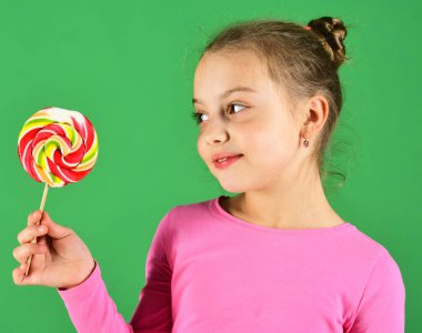 Kız büyük renkli tatlı karamel yiyor. Gülümseyen yüzlü çocuk