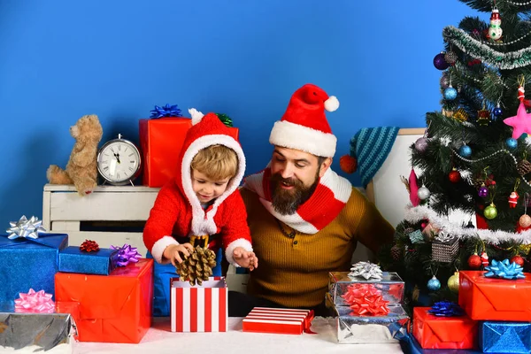 Weihnachtsmann und kleiner Helfer inmitten von Geschenkboxen am Weihnachtsbaum — Stockfoto