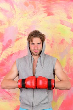 Gri kolsuz kapüşonlu adam kırmızı boks eldiveni giyiyor.