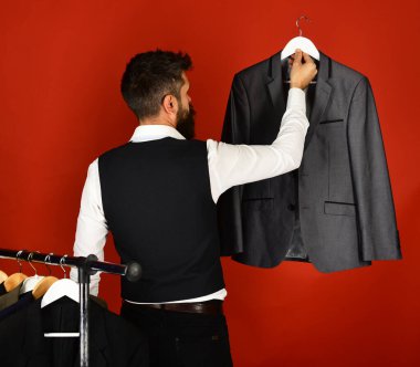 İş adamı kırmızı arka plandaki ceketlerin yanında. İş modası ve alışveriş