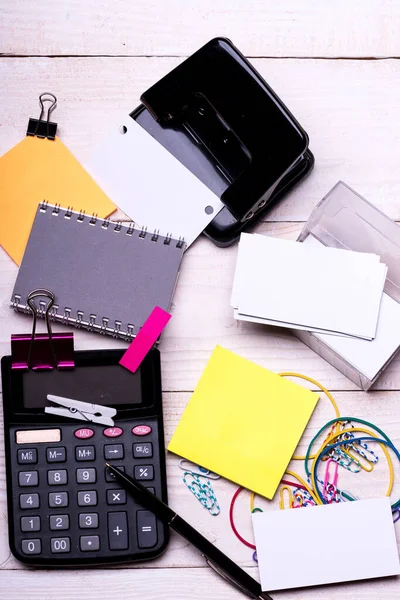 Notebook and puncher near pen on white wooden background Royalty Free Stock Photos