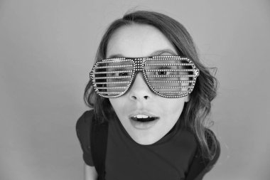 küçük kız okul üniforması. Eğlence için parti gözlükleri. Çocuk modası konsepti. Gözlüklere odaklanıyorum. Havalı görünümlü turuncu arka plan. Güzel ve şık bir çocuk. Parti Elementleri