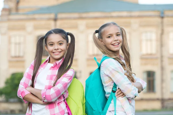 Se acabaron las vacaciones. De vuelta a la escuela. Colegialas lindas con colas de caballo largas. Fin del año escolar. Alegre colegialas inteligentes. Colegialas felices al aire libre. Colegialas pequeñas con mochilas. Septiembre —  Fotos de Stock