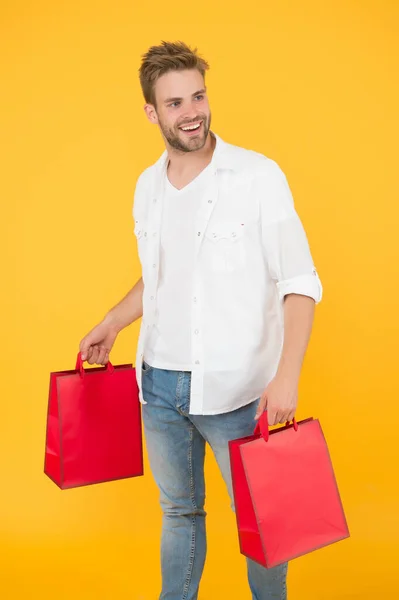 Bonito homem atraente sorrindo enquanto faz compras. Um verdadeiro viciado em compras. comprar presentes e presentes online. Um tipo a fazer compras. assistente de loja com sacos de embalagem. entrega de compra durante a quarentena — Fotografia de Stock